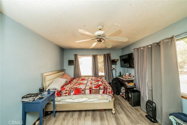 bedroom with a textured ceiling, wood finished floors, and a ceiling fan