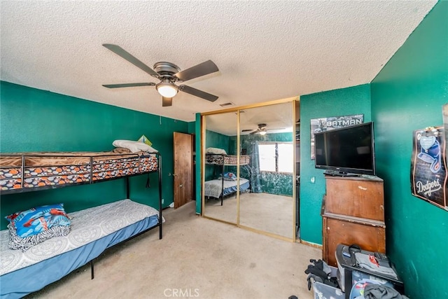 bedroom with a textured ceiling, ceiling fan, visible vents, a closet, and carpet