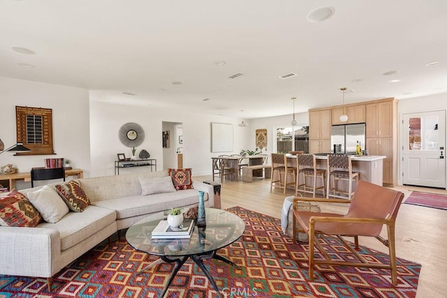 living area featuring light wood-type flooring and visible vents