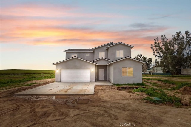 traditional home featuring a garage, driveway, and stucco siding