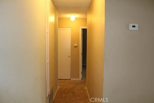 hallway with carpet, visible vents, and a textured ceiling