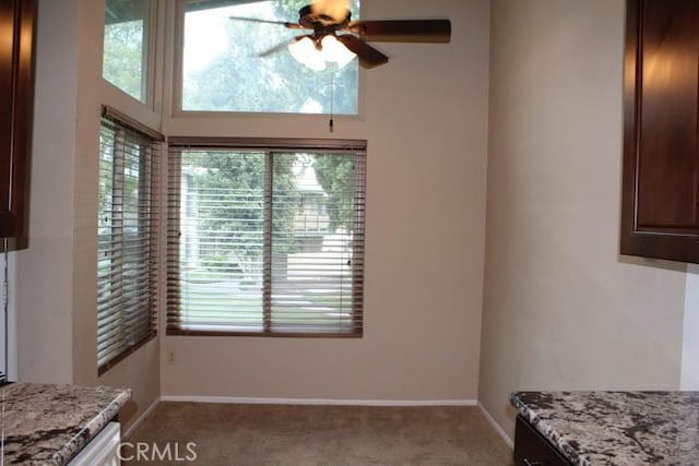 unfurnished dining area featuring light carpet, ceiling fan, and baseboards