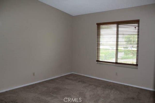 carpeted spare room featuring baseboards