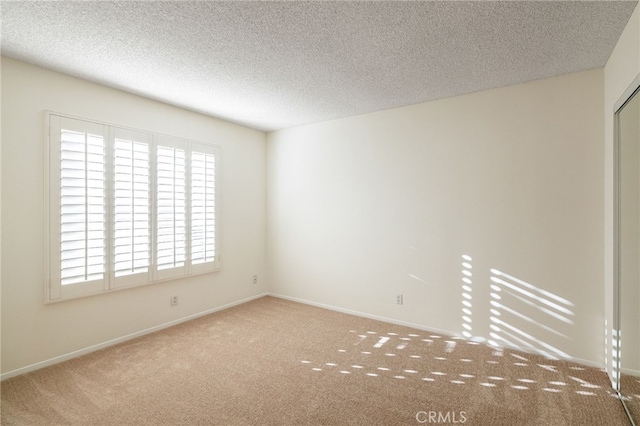 unfurnished room with baseboards, a textured ceiling, and carpet flooring