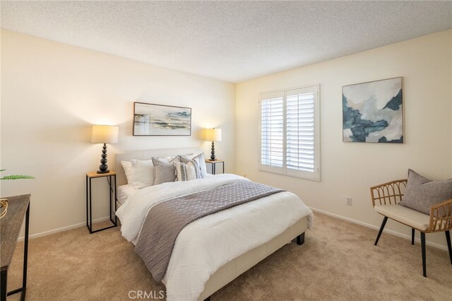 bedroom with light colored carpet, baseboards, and a textured ceiling