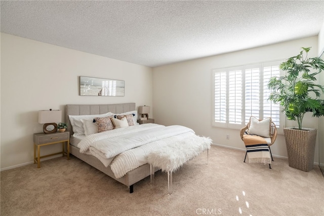 bedroom featuring a textured ceiling, baseboards, and light carpet