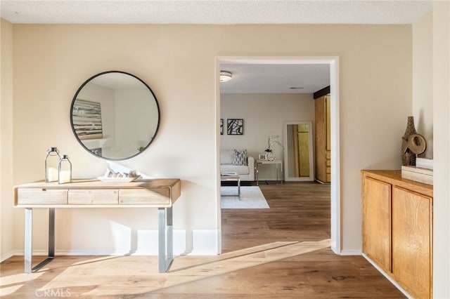 corridor featuring baseboards, a textured ceiling, and wood finished floors