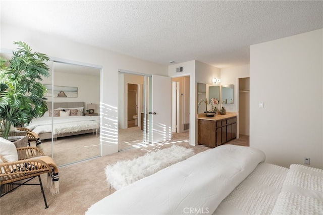 bedroom with visible vents, light colored carpet, and a textured ceiling