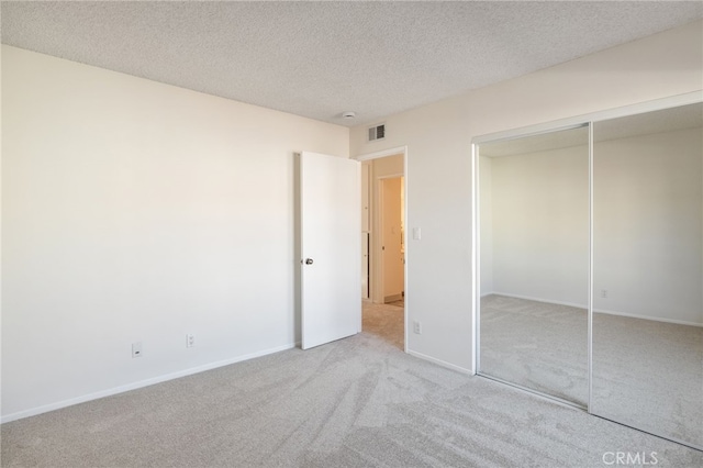 unfurnished bedroom with carpet floors, visible vents, a closet, and a textured ceiling