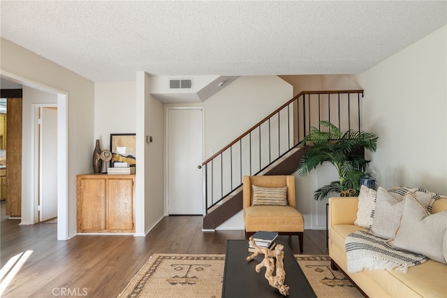 living area featuring stairs, wood finished floors, visible vents, and a textured ceiling