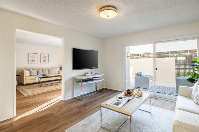 living area featuring wood finished floors, baseboards, and a textured ceiling