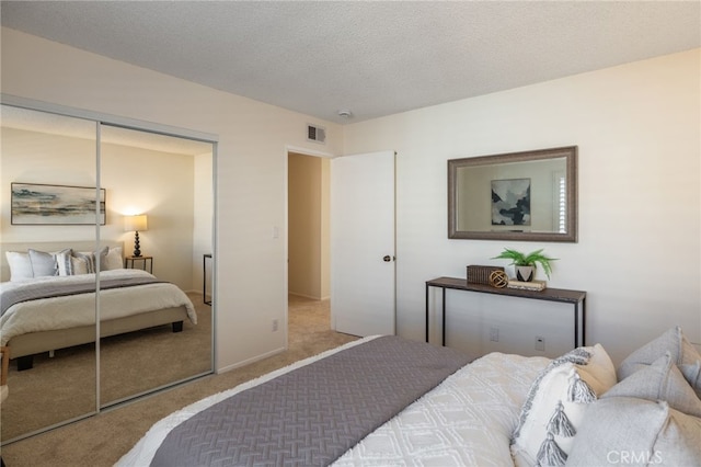 bedroom with carpet flooring, visible vents, a closet, and a textured ceiling