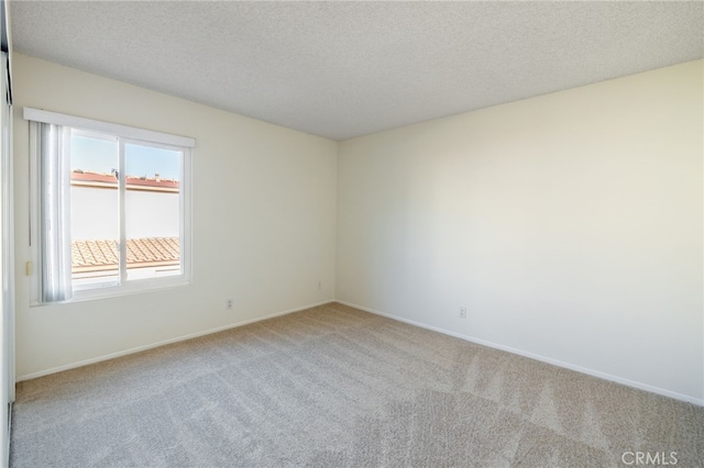 spare room featuring a textured ceiling, baseboards, and carpet floors