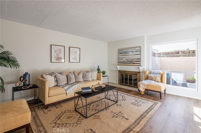 living room with a fireplace, wood finished floors, and a textured ceiling