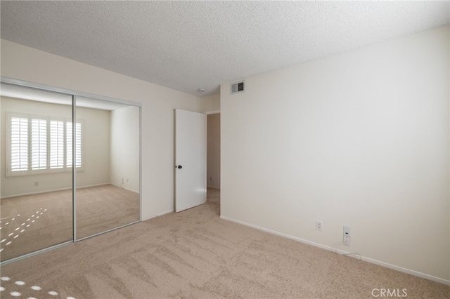 unfurnished bedroom with carpet flooring, visible vents, a closet, and a textured ceiling