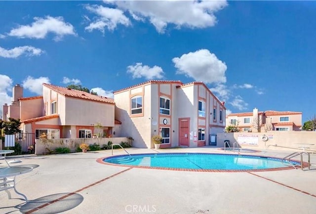 community pool with a patio and fence