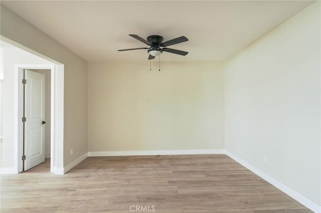 empty room featuring light wood-style floors, baseboards, and a ceiling fan