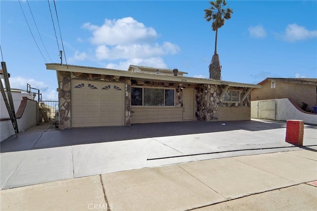 ranch-style home featuring driveway, an attached garage, and fence