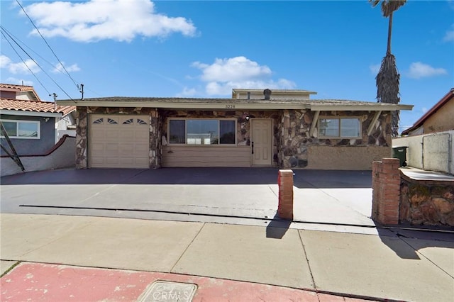 view of front of house featuring stone siding, driveway, and an attached garage