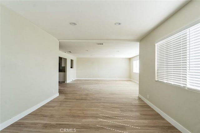 spare room with light wood finished floors, recessed lighting, visible vents, and baseboards