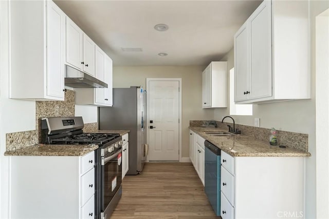 kitchen with under cabinet range hood, a sink, white cabinetry, light wood-style floors, and appliances with stainless steel finishes