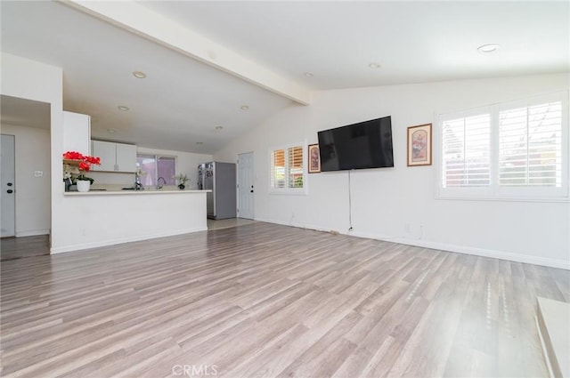 unfurnished living room featuring baseboards, lofted ceiling with beams, and light wood finished floors