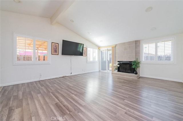 unfurnished living room featuring a healthy amount of sunlight, lofted ceiling with beams, and wood finished floors