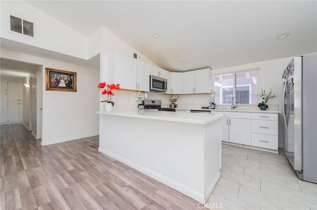 kitchen featuring a peninsula, visible vents, vaulted ceiling, light countertops, and appliances with stainless steel finishes