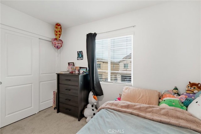 bedroom featuring multiple windows, a closet, and light colored carpet