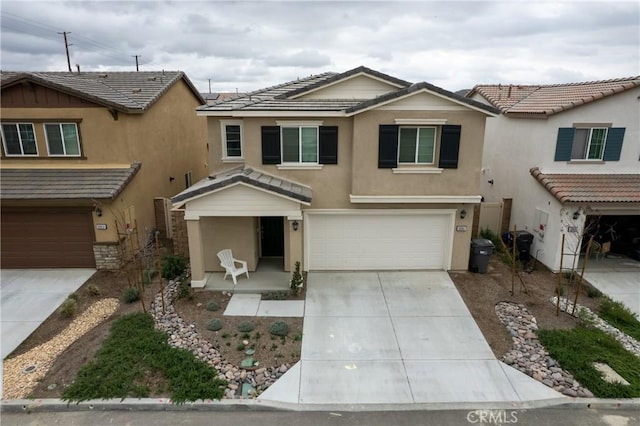 view of front of home with driveway, an attached garage, a tiled roof, and stucco siding