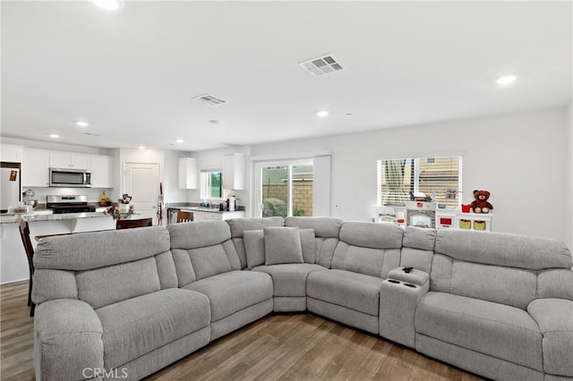 living room with visible vents, wood finished floors, and recessed lighting