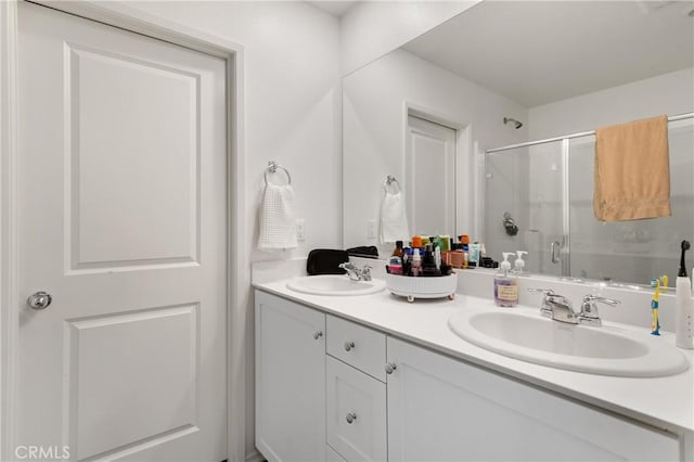 full bath featuring double vanity, a sink, and a shower stall