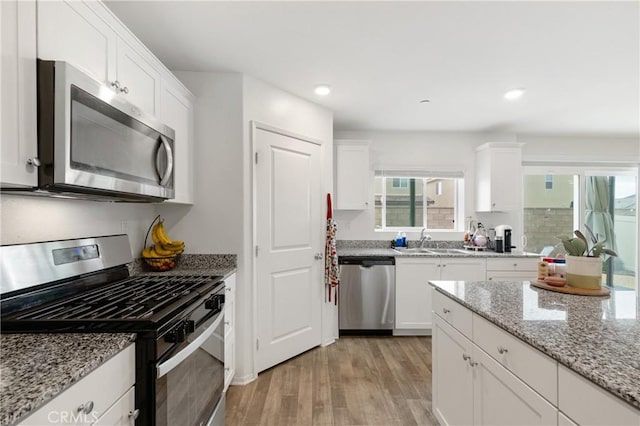 kitchen featuring light wood-style floors, white cabinetry, stainless steel appliances, and a sink