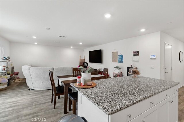 kitchen featuring light wood finished floors, light stone counters, open floor plan, and recessed lighting