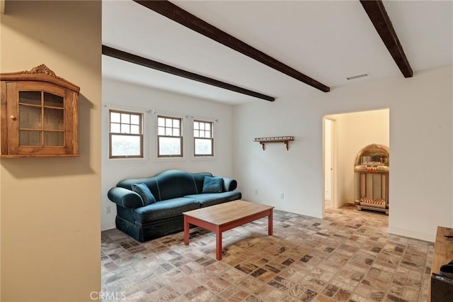 living area with brick floor, beam ceiling, visible vents, and baseboards