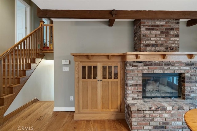 interior space with beamed ceiling, a fireplace, wood finished floors, and baseboards