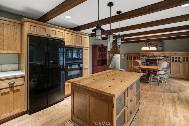 kitchen featuring butcher block countertops, light wood-style floors, light brown cabinetry, beam ceiling, and black appliances