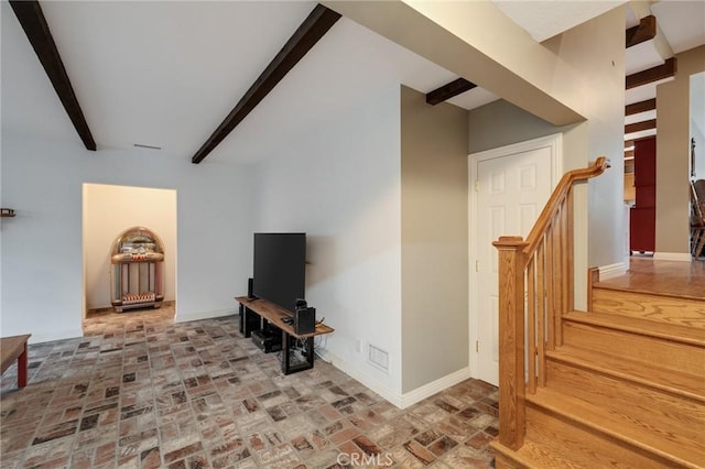 living area with brick floor, stairs, baseboards, and beam ceiling