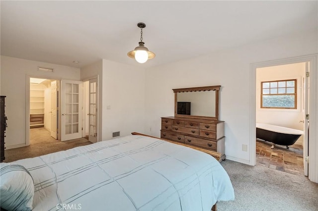 carpeted bedroom featuring a walk in closet, visible vents, and baseboards