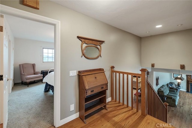 corridor featuring recessed lighting, baseboards, an upstairs landing, and wood finished floors