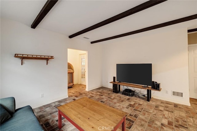 living area with beamed ceiling, brick floor, visible vents, and baseboards