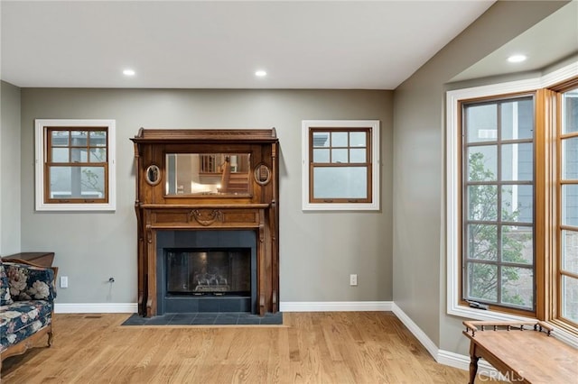 living area with a fireplace with flush hearth, recessed lighting, wood finished floors, and baseboards