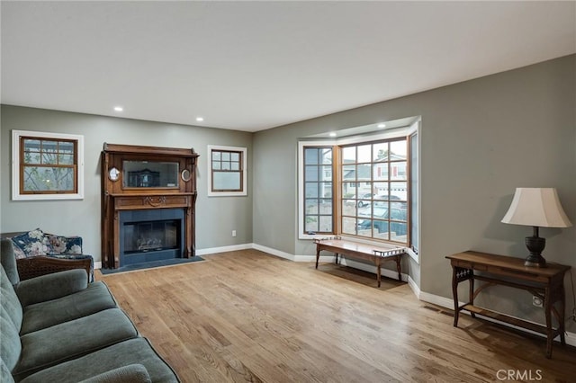 living room featuring recessed lighting, a fireplace, light wood-style flooring, and baseboards