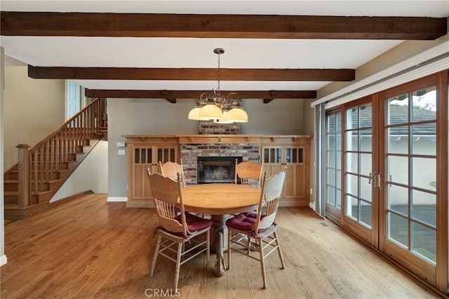 dining space featuring baseboards, stairway, a chandelier, and wood finished floors