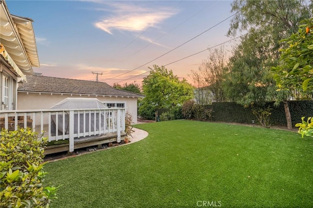 yard at dusk featuring a fenced backyard and a deck