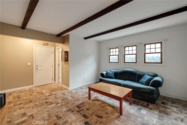 living room with brick floor, beam ceiling, and baseboards