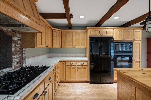 kitchen with beam ceiling, tile countertops, custom exhaust hood, light wood-style flooring, and black appliances