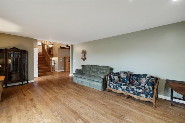 living area with stairs, baseboards, and wood finished floors