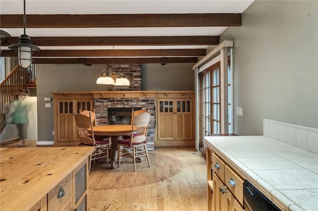 dining room with stairs, light wood-type flooring, and beam ceiling