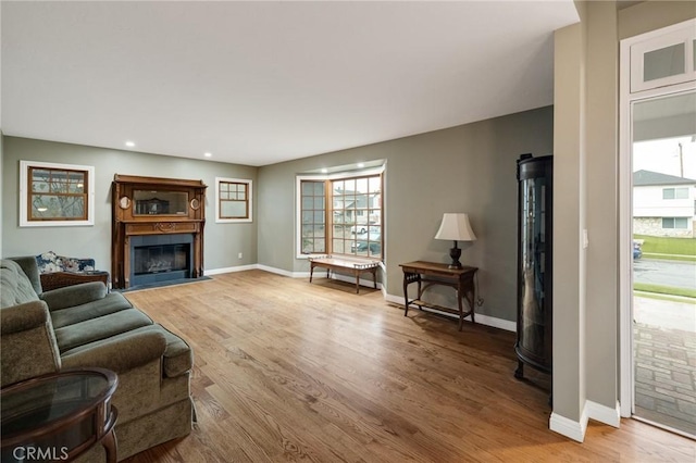 living area with light wood-style floors, a fireplace with flush hearth, baseboards, and recessed lighting